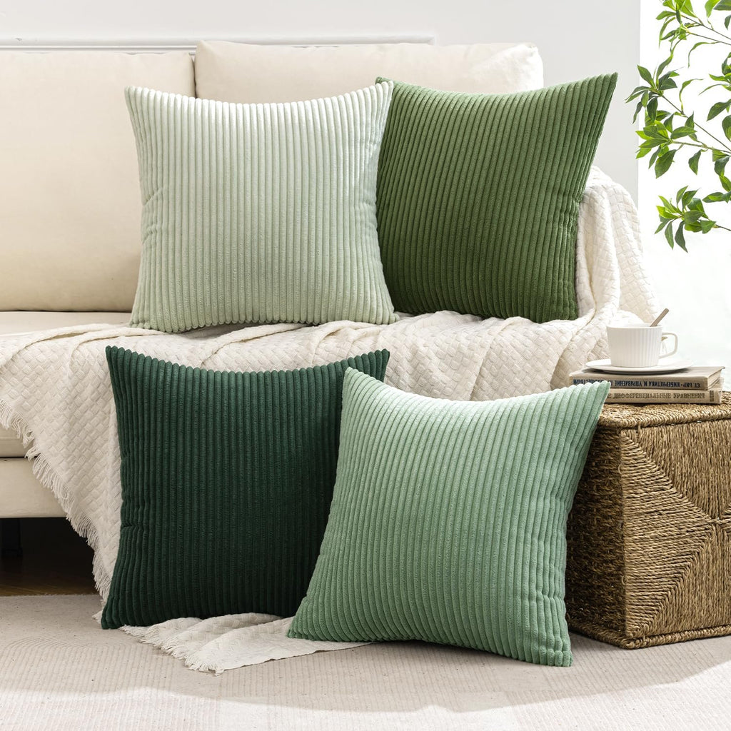 Four sage green corduroy throw pillow covers arranged on a couch with a woven basket and books nearby.