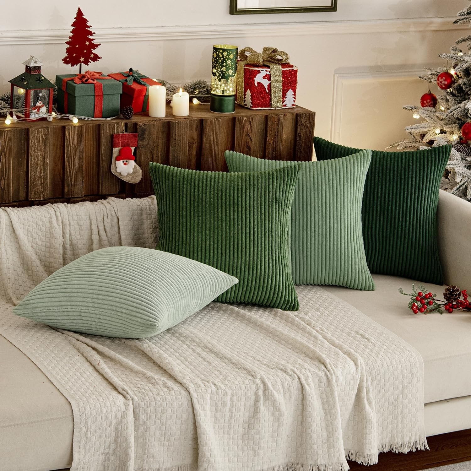 Four sage green corduroy throw pillow covers arranged on a couch with a Christmas-themed background.