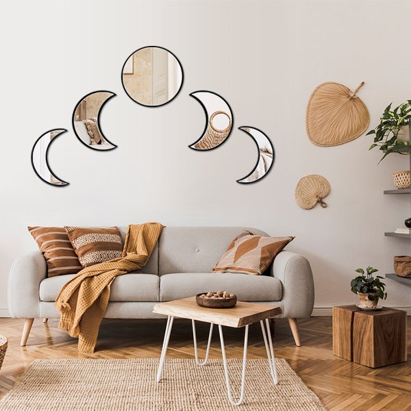 Five acrylic moon phase mirrors with black frames arranged above a sofa in a living room setting.