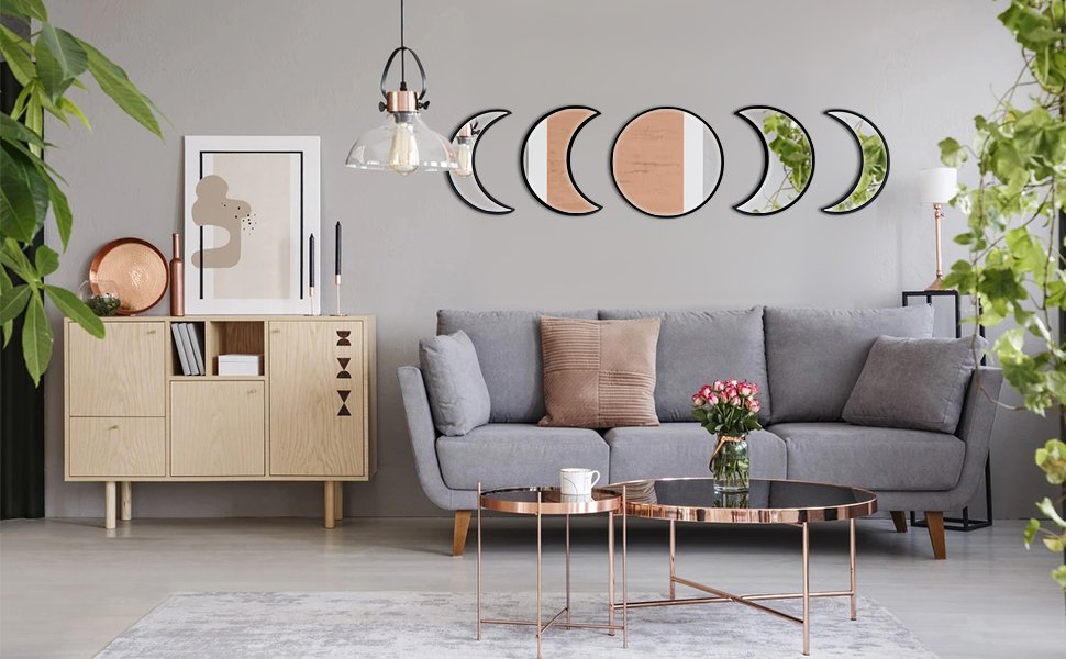 Five acrylic moon phase mirrors with black frames mounted on a gray wall above a sofa.