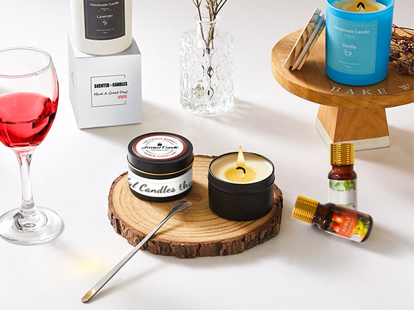 Various scented candles and fragrance oils arranged on a white surface with a wine glass and wooden elements.