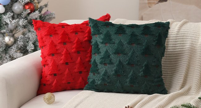 Two Christmas tree patterned pillow covers, one red and one green, on a sofa with a Christmas tree in the background.