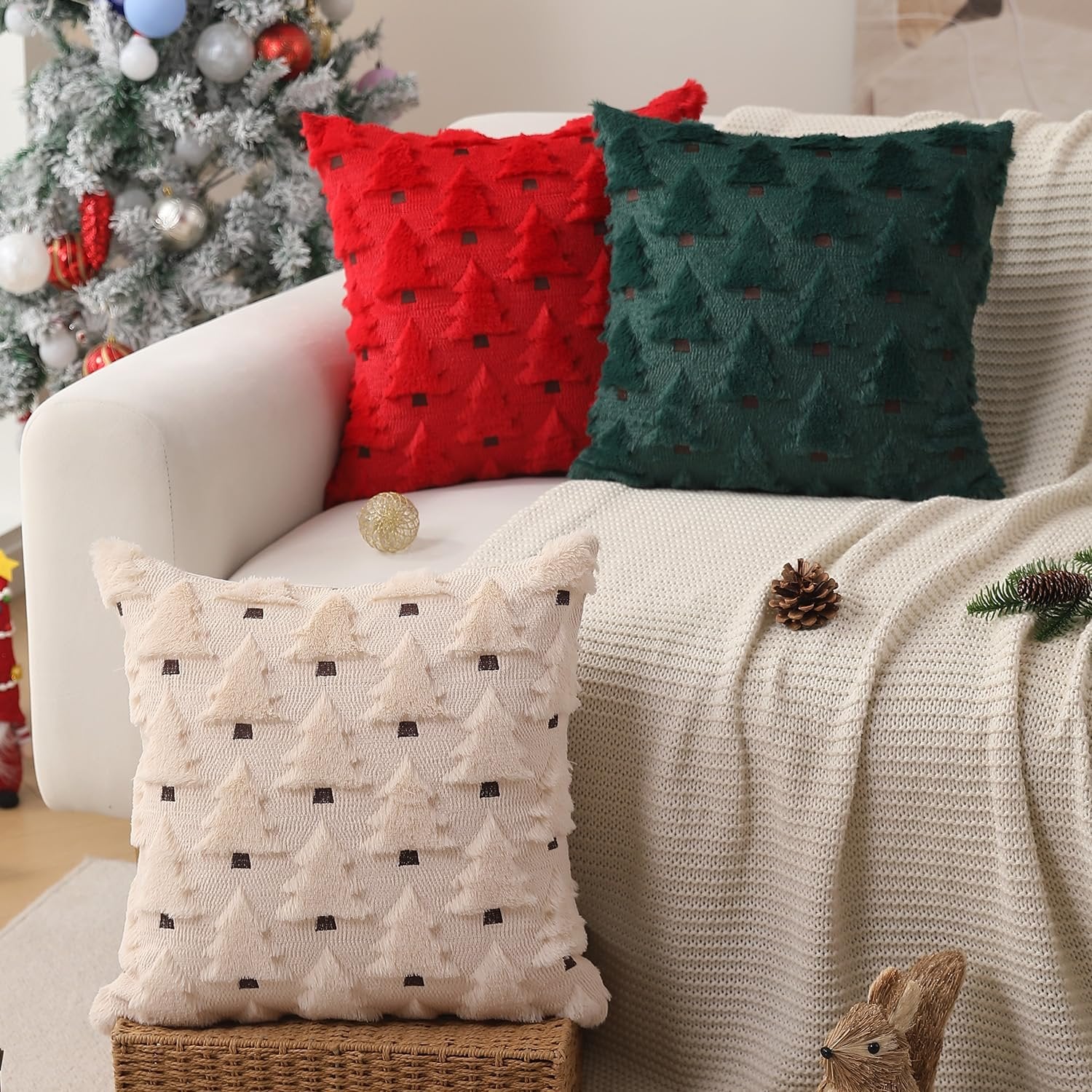 Three Christmas-themed throw pillow covers with textured tree patterns displayed on a sofa next to a decorated Christmas tree.