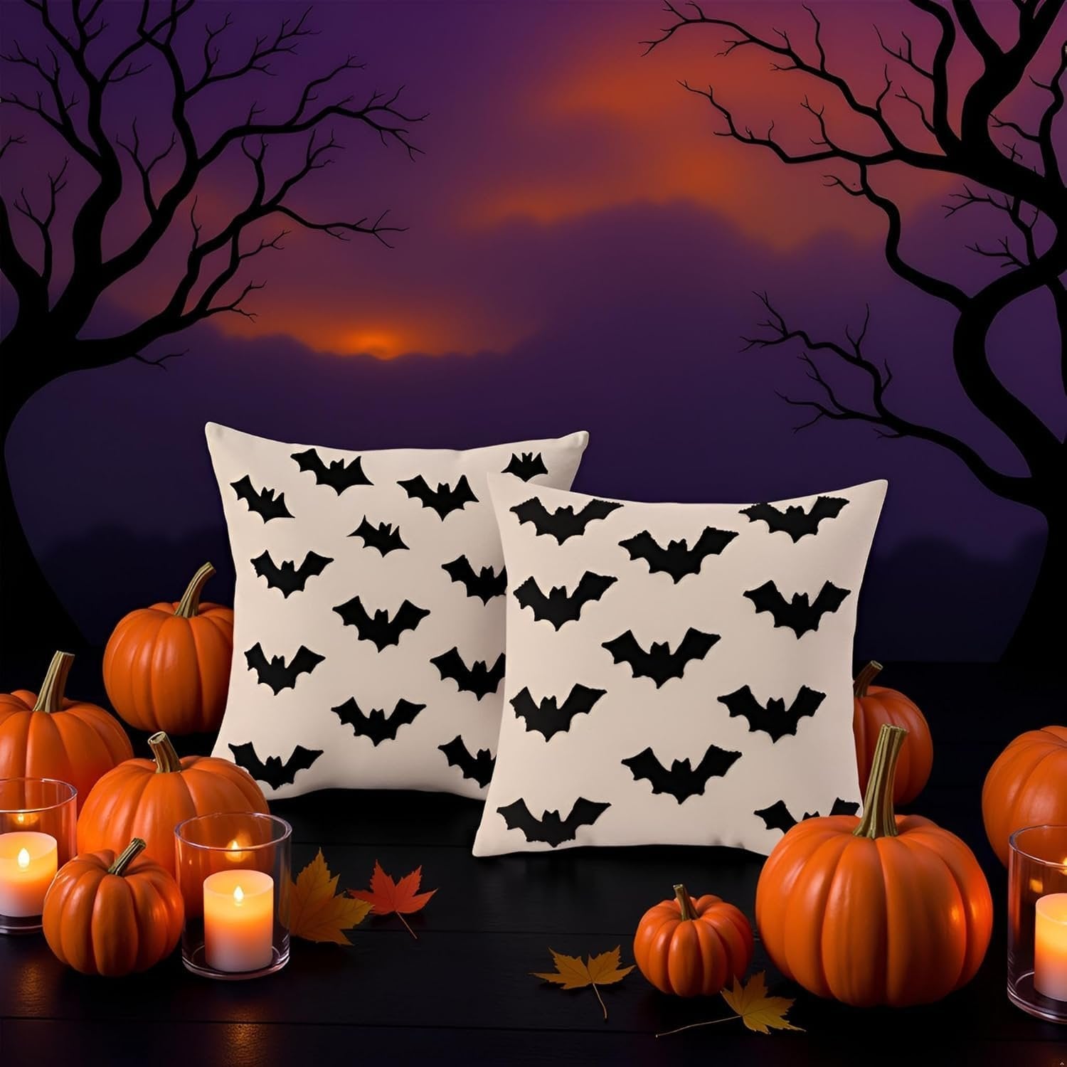 Two cream-colored Halloween pillow covers with black bat patterns, displayed with pumpkins and candles on a dark surface against a spooky tree and sunset background.
