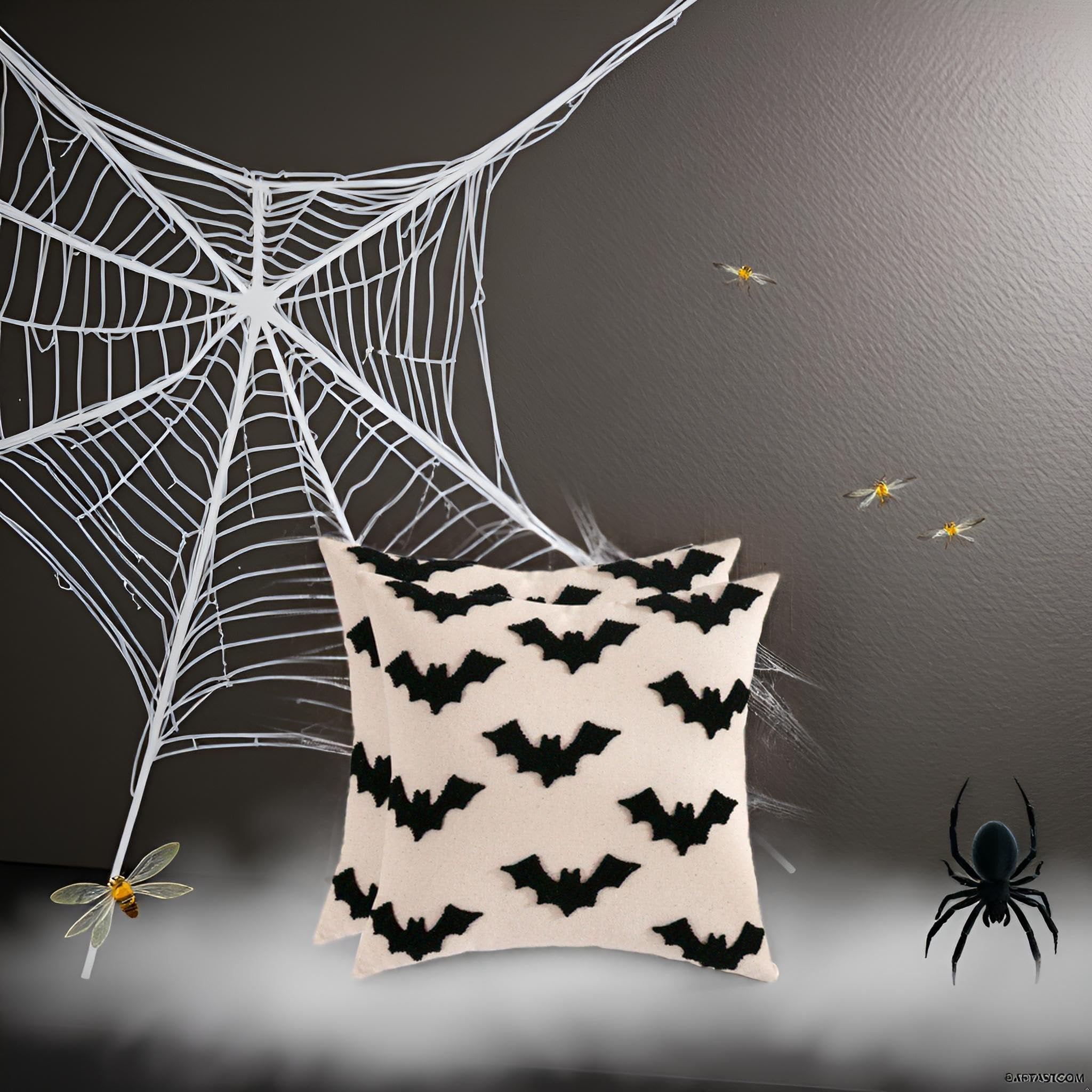 Two cream-colored Halloween pillow covers with black embroidered bats, displayed with a large white spiderweb and decorative insects.