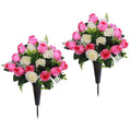 Two artificial cemetery flower bouquets with pink and white roses and green foliage in dark vases with stakes, isolated on white.