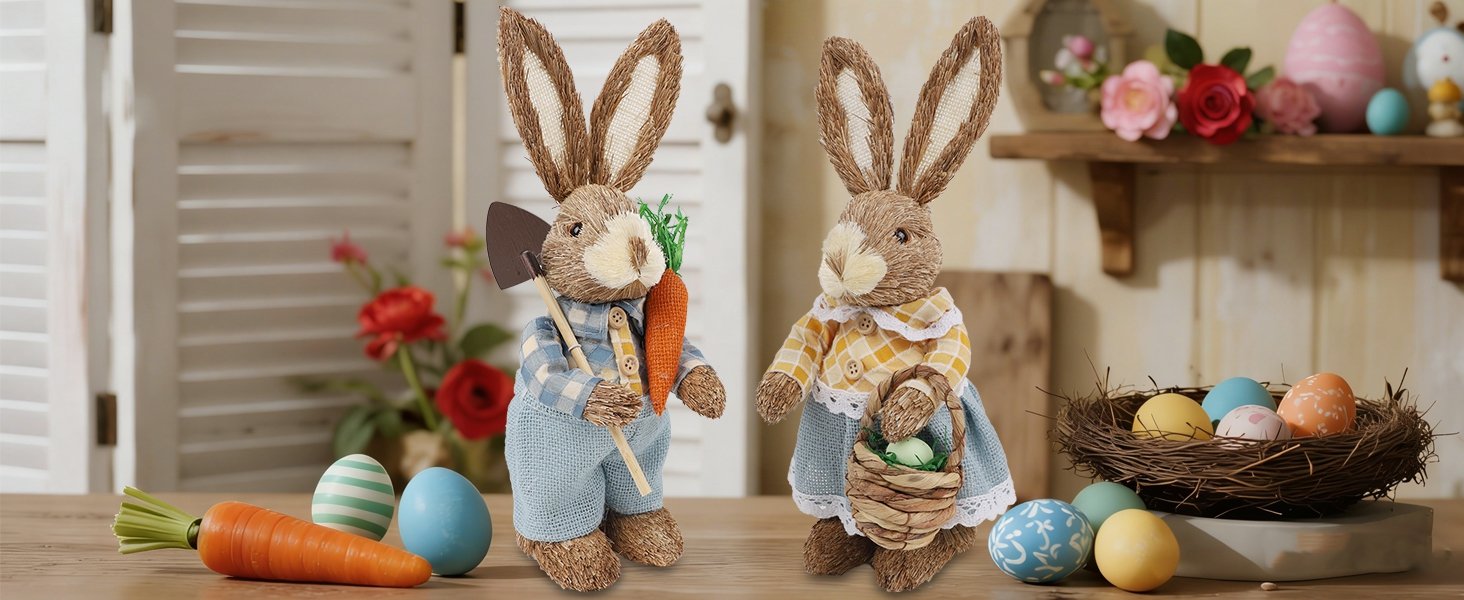 Two rustic straw Easter bunny figurines, one holding a shovel and carrot, the other a basket with an egg, with decorative eggs and flowers.