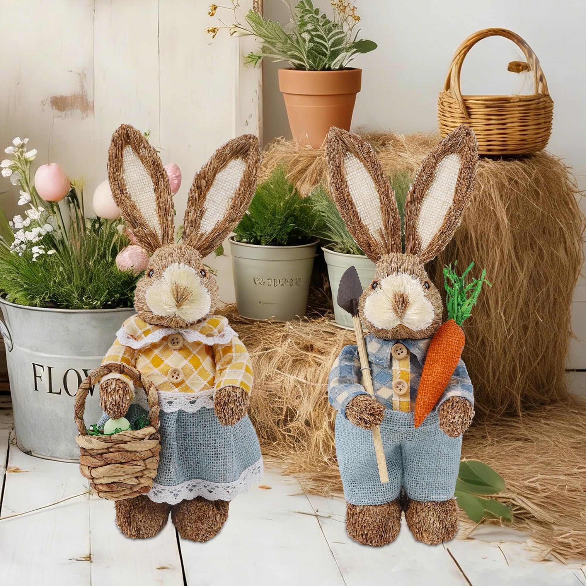 Two rustic Easter bunny figurines, one holding a basket with an egg, the other holding a carrot and shovel, on a hay bale.