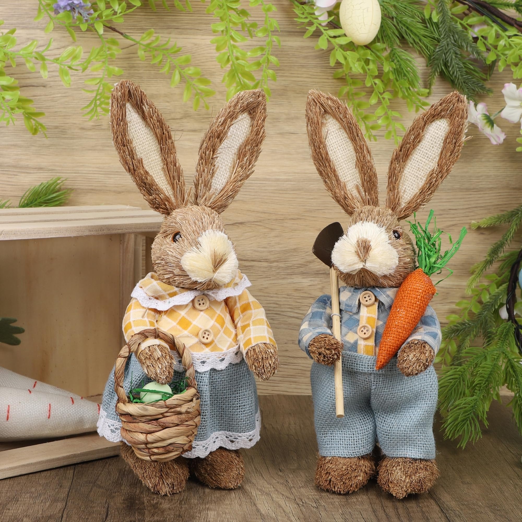Two straw and sisal Easter bunny figurines on a wooden surface with decorative greenery.