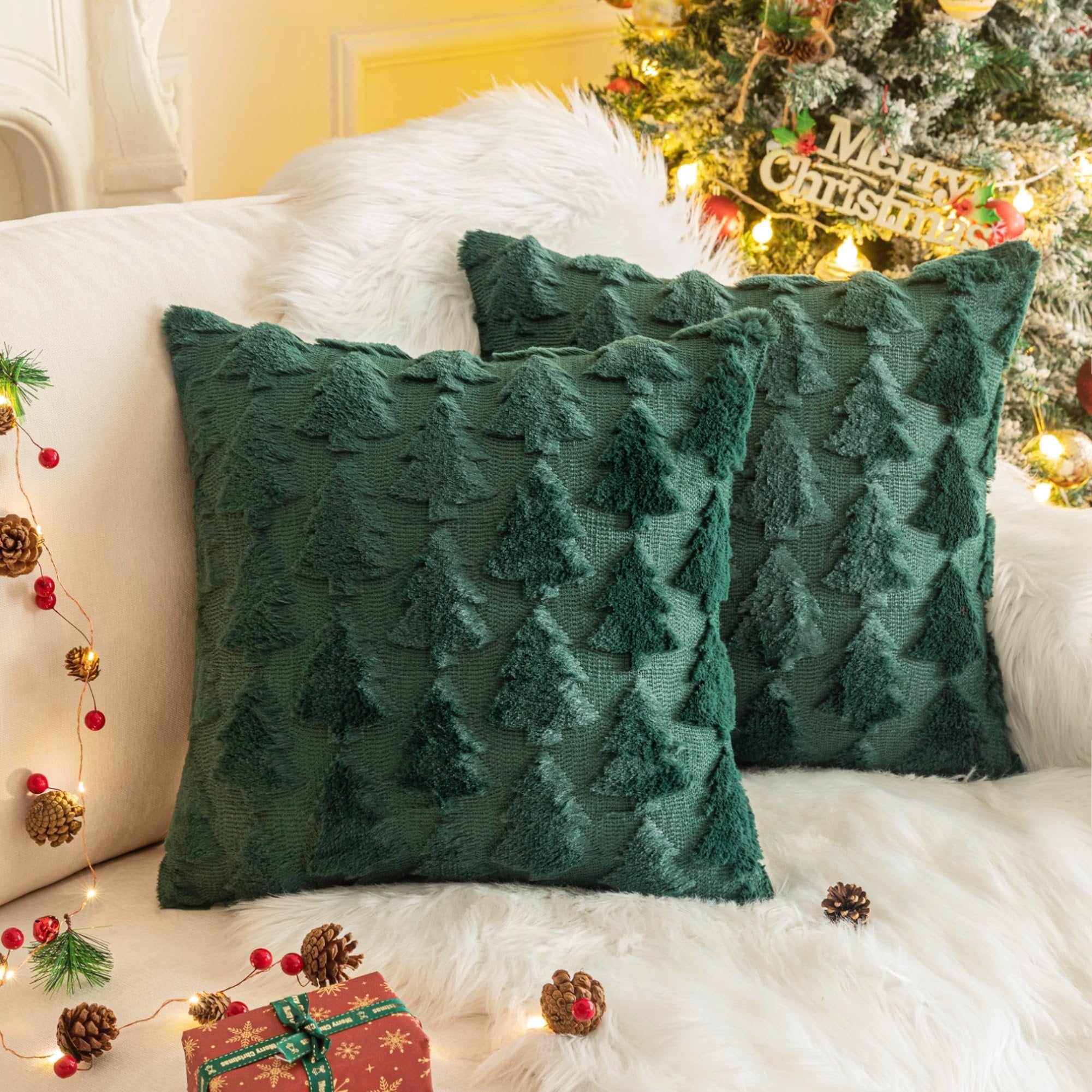Two green Christmas throw pillow covers with textured tree patterns on a white couch with a Christmas tree in the background.
