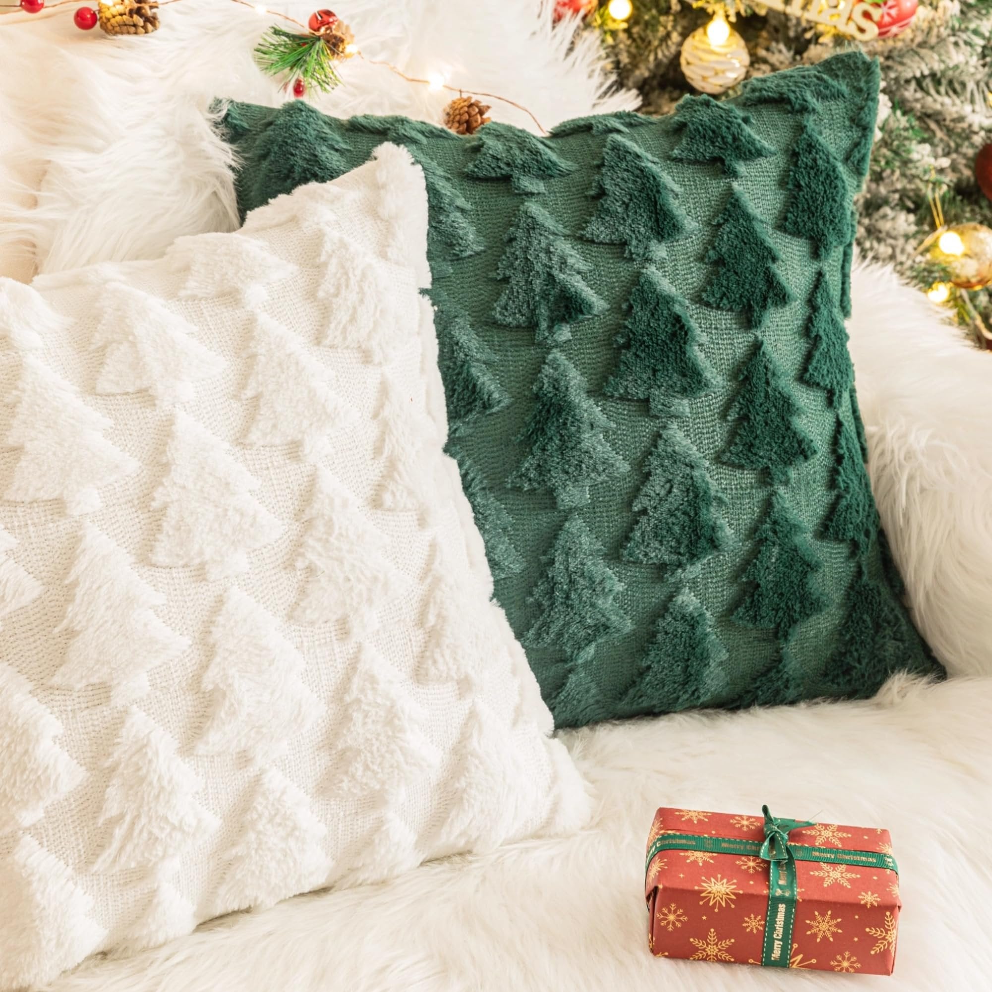 Two textured Christmas throw pillow covers, one white and one green, with a festive gift box on a white fluffy surface.