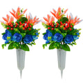 Two artificial cemetery flower bouquets with orange lilies, blue roses, and red berries in plastic vases with ground spikes.