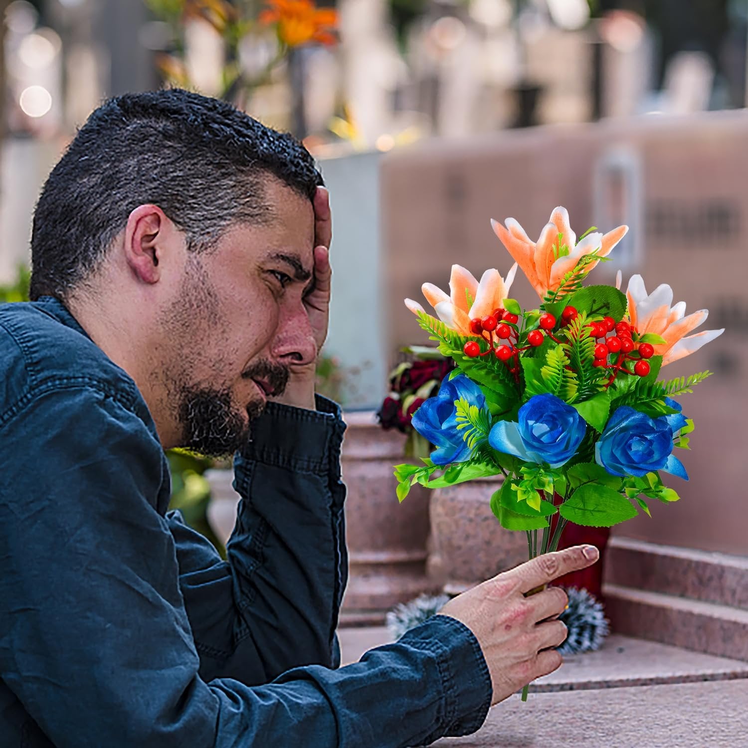 Man holding artificial cemetery flower bouquet with lilies, roses, and berries near a headstone
