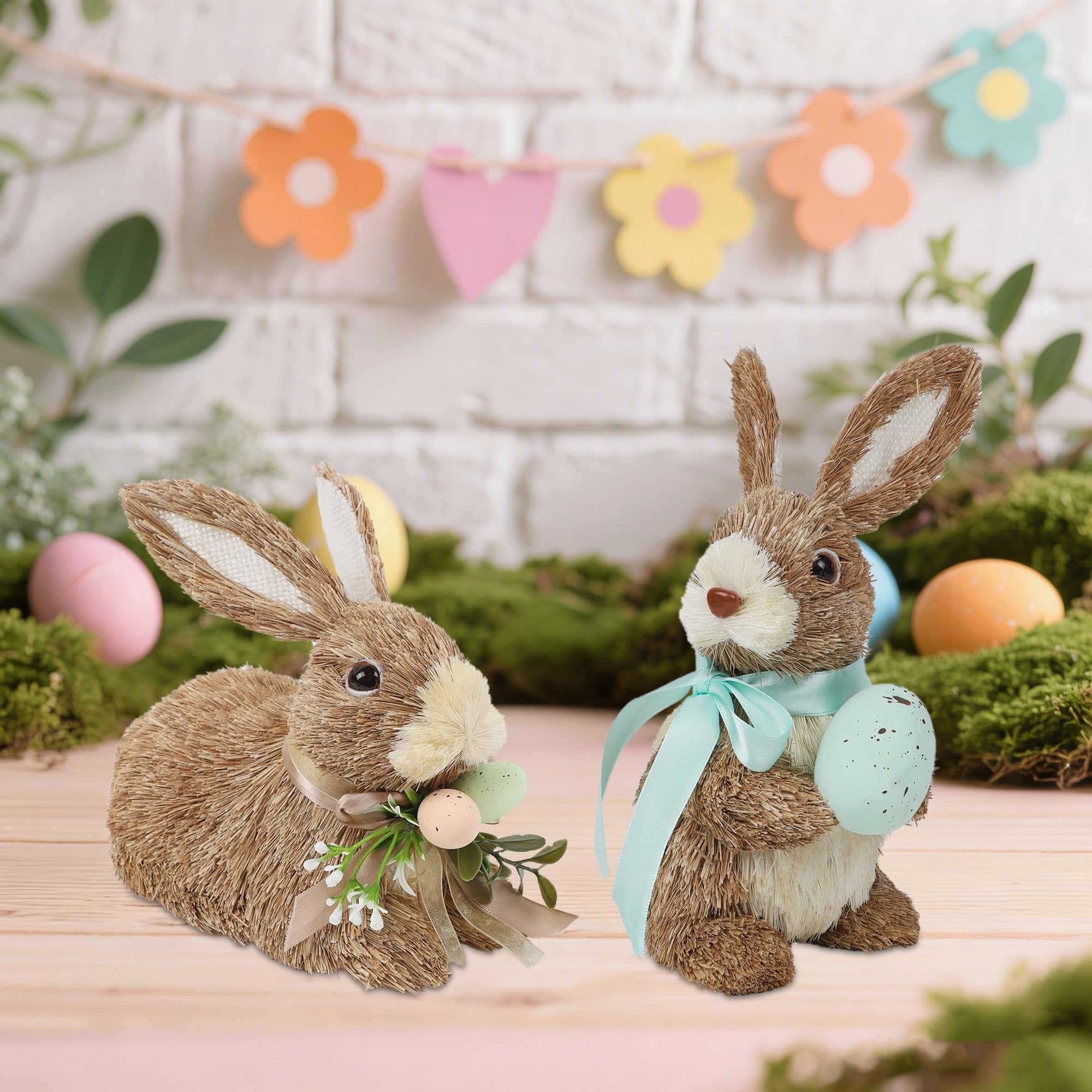 Two sisal bunny figurines decorated for Easter with eggs and ribbons on a wooden surface.