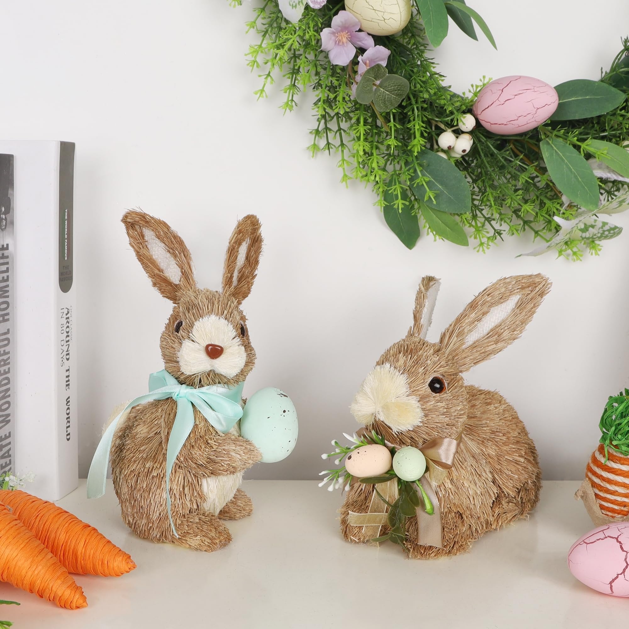 Two sisal bunny figurines with Easter eggs and ribbons, displayed with books and carrots.