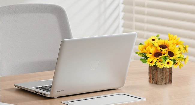 Artificial silk sunflowers in a rustic wood pot on a desk next to a laptop.