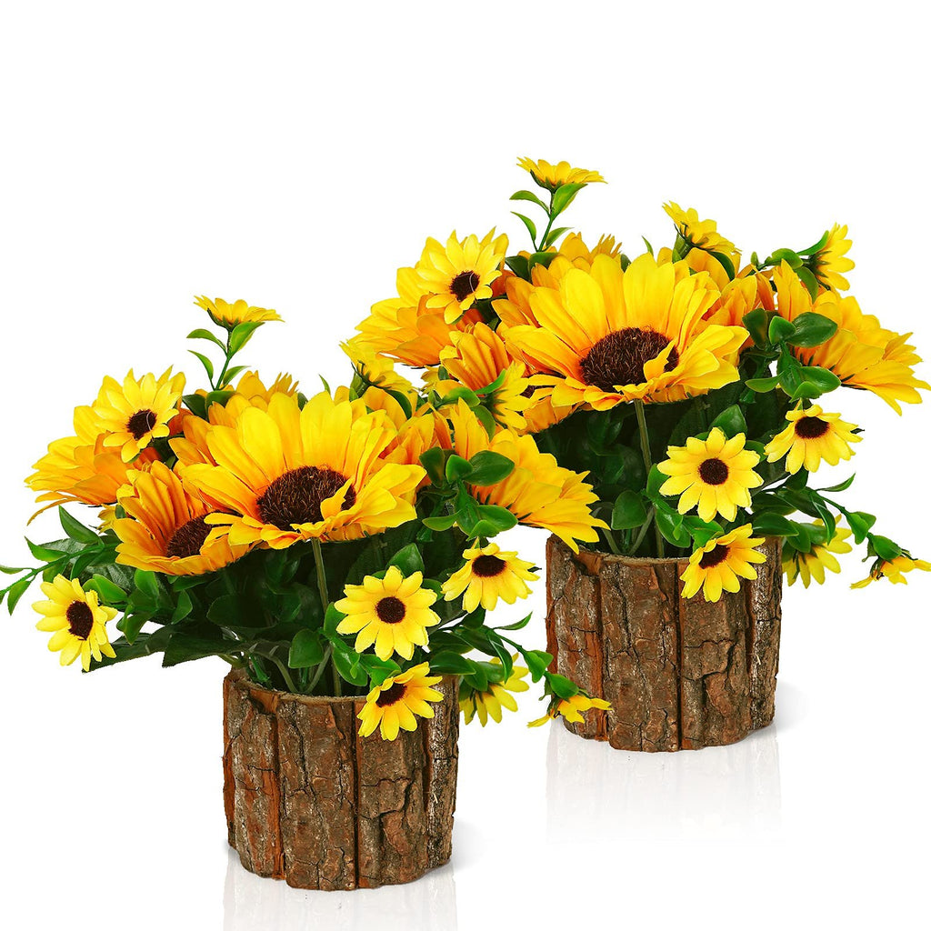 Two potted artificial silk sunflowers with green leaves in rustic bark-textured pots, displayed against a white background.