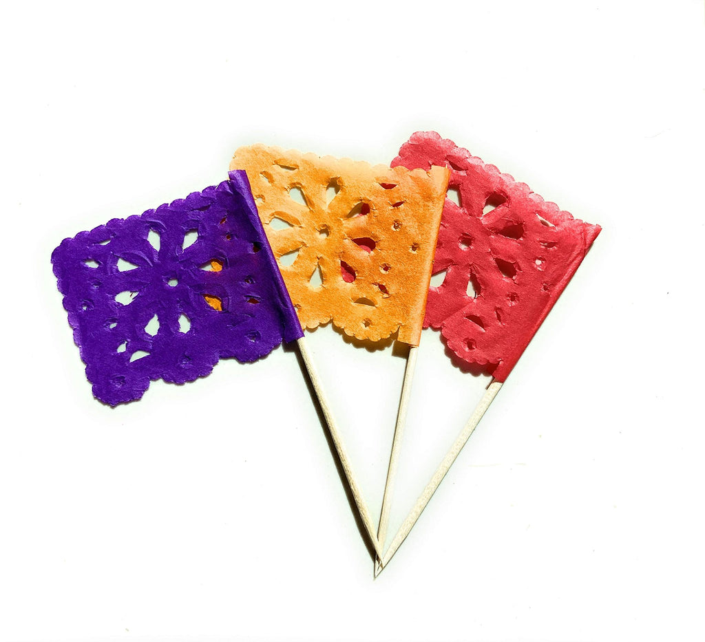 Three mini papel picado tissue paper flag picks in purple, orange, and red on wooden sticks, isolated on white.