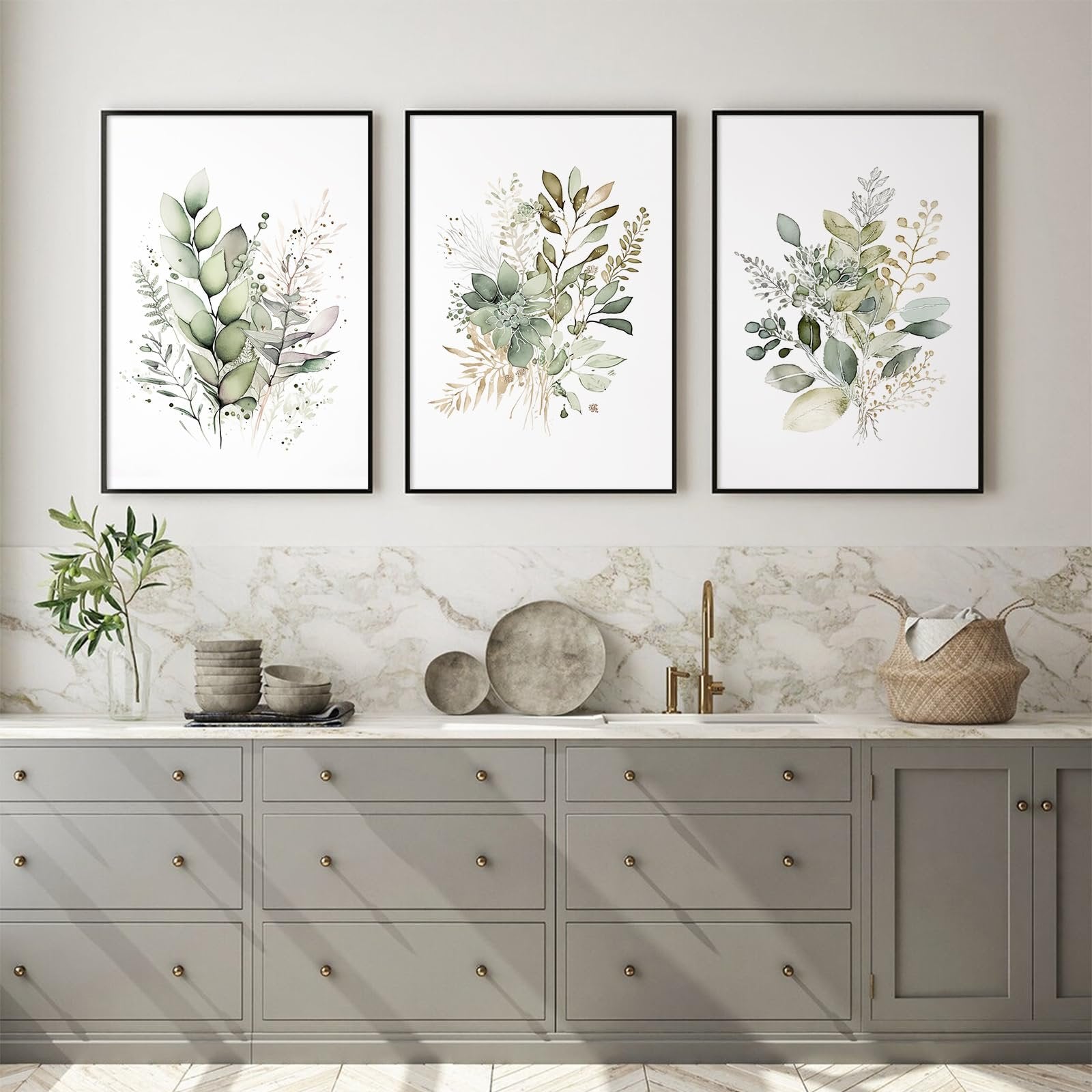 Three framed watercolor botanical prints with sage green leaves and wildflowers displayed above a kitchen counter.
