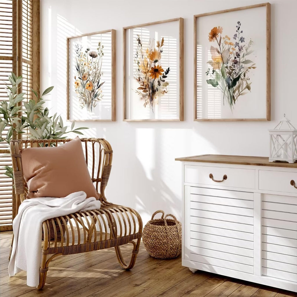 Three framed botanical watercolor prints of wildflowers hanging on a white wall above a white cabinet.