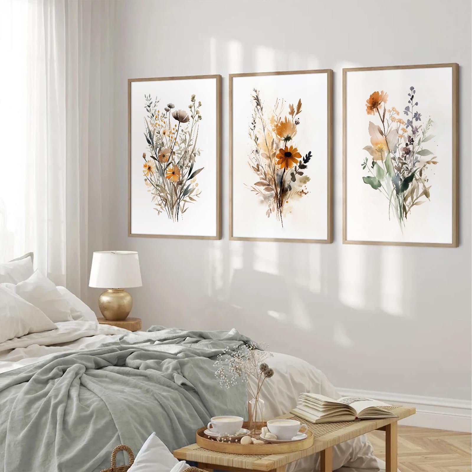 Three framed botanical wall art prints with wildflowers displayed above a bed in a bedroom setting.
