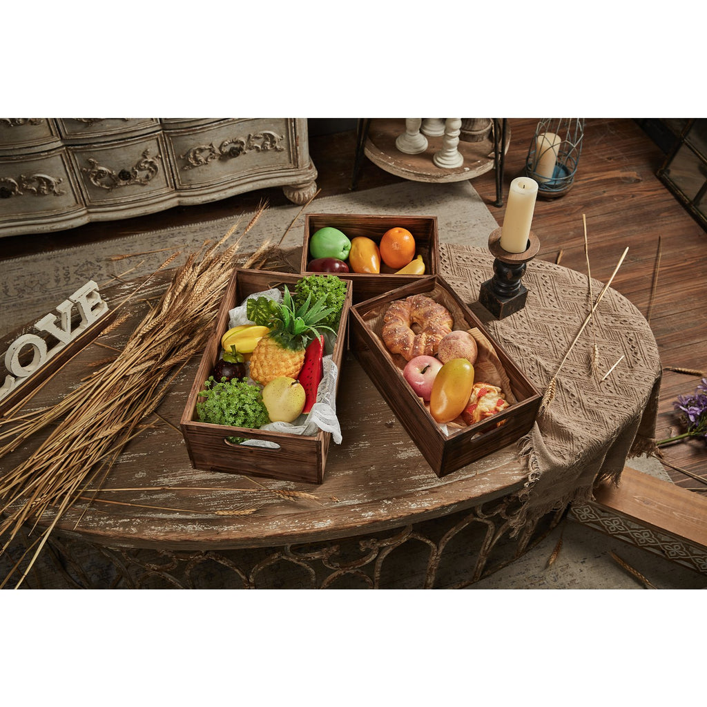 Three distressed fir wood crates filled with faux fruits and baked goods on a rustic table.