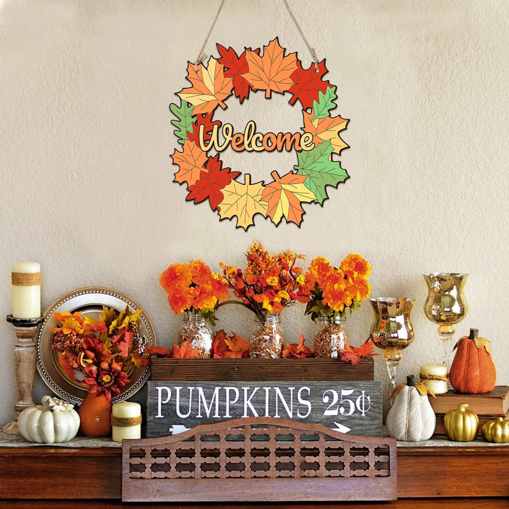 Fall maple leaf wreath with 'Welcome' text hanging on a wall above a shelf with autumn decor