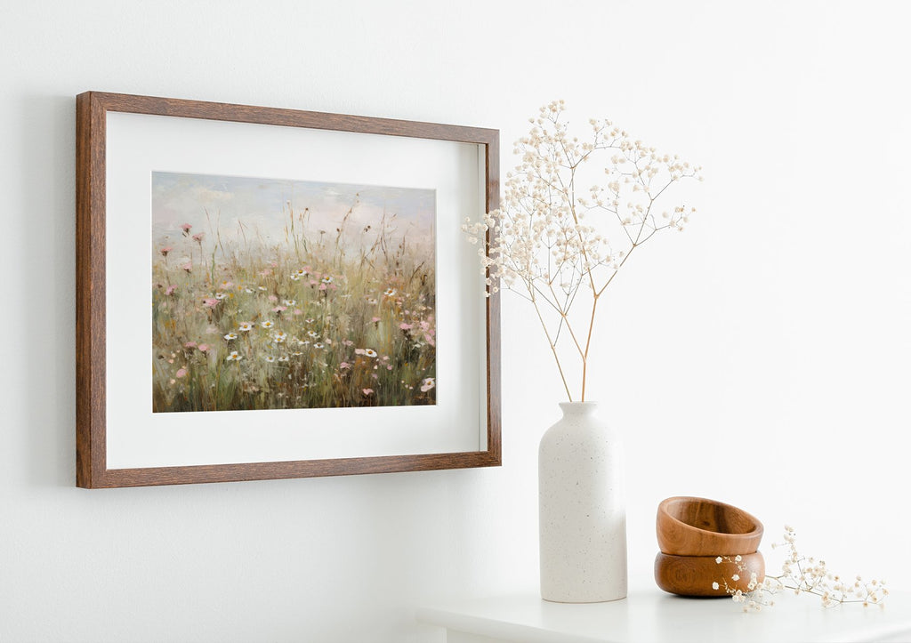 Framed vintage wildflower art print on a white wall next to a vase with dried flowers and wooden bowls.