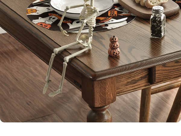 Halloween placemat with ghosts and pumpkins on a wooden table with a skeleton decoration