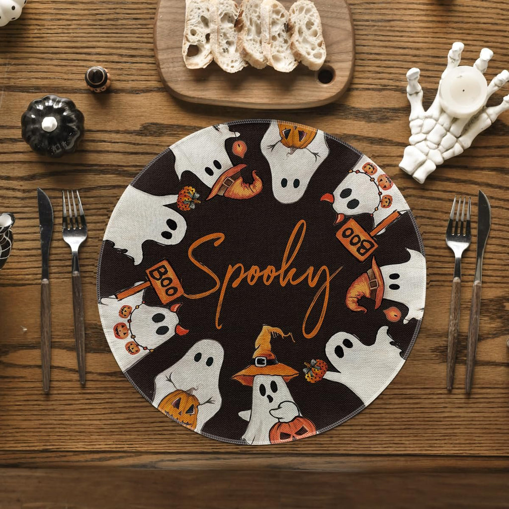 Round Halloween placemat with ghosts, pumpkins, and the word Spooky in the center, set on a wooden table with cutlery and bread.