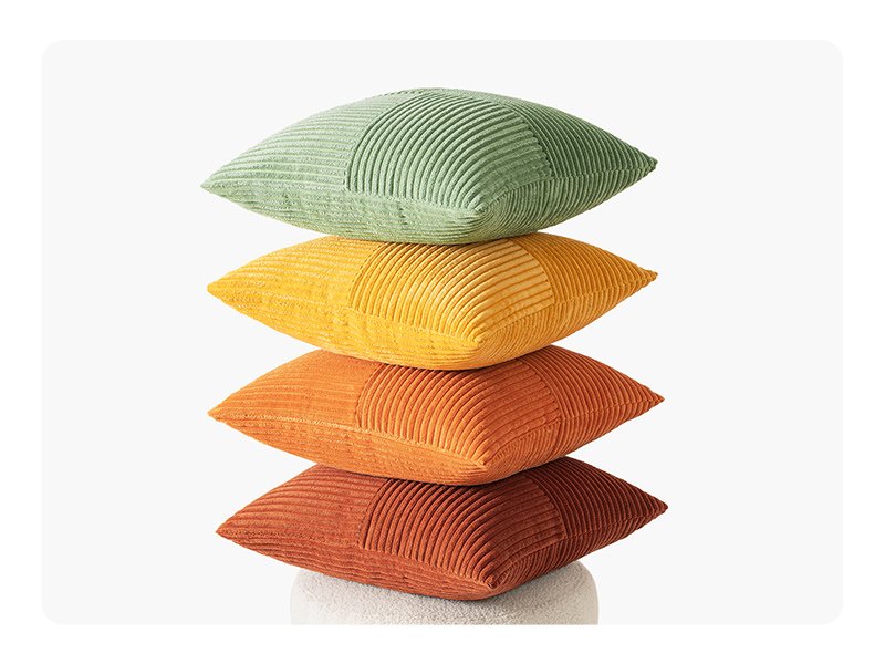 Stack of four corduroy patchwork throw pillow covers in green, yellow, orange, and rust colors on a white background.