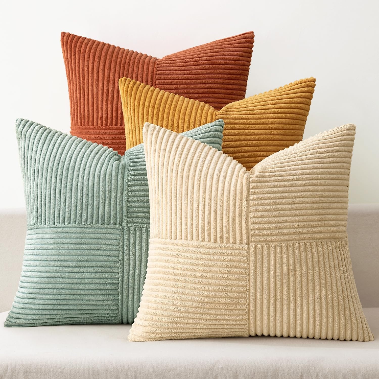 Stack of five corduroy patchwork throw pillow covers in various colors including teal, orange, yellow, and cream.