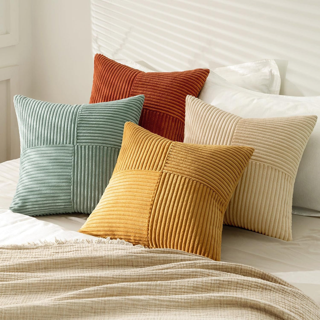 Set of five corduroy patchwork throw pillow covers in teal, rust, yellow, and beige arranged on a bed with a textured throw blanket.