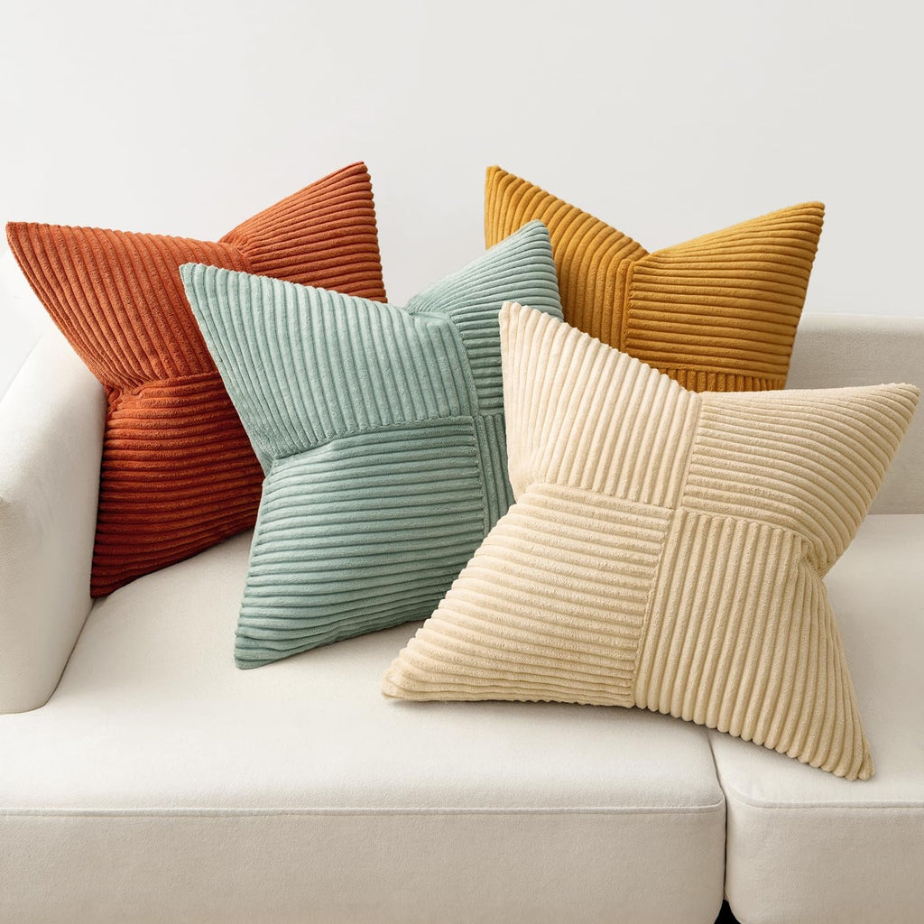 Four corduroy patchwork throw pillow covers in various colors arranged on a white sofa.