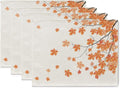 Set of four fall placemats with autumn maple leaves design, shown from an angled top-down view.