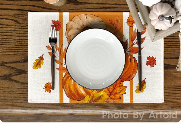 Fall pumpkin and leaf placemat set with a plate, fork, and knife on a wooden table