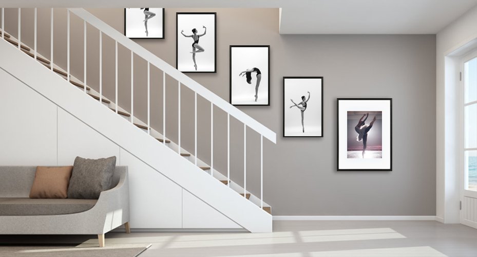 Five framed ballet dancer prints displayed on a wall next to a staircase and sofa.