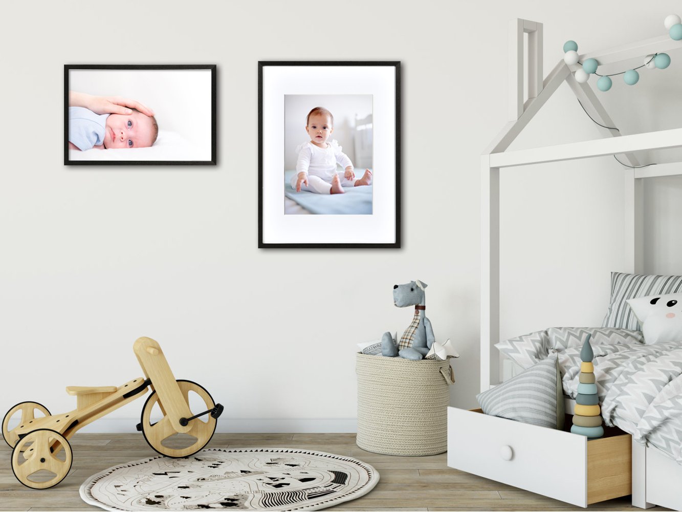 Nursery room with two framed baby photos on the wall, a wooden toy, and a bed.