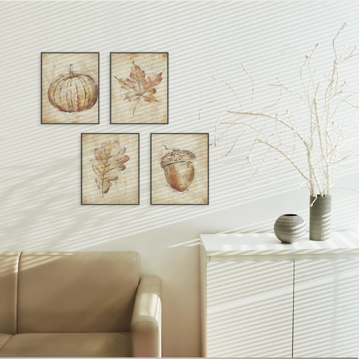 Four unframed vintage fall wall art prints featuring a pumpkin, maple leaf, oak leaf, and acorn on a textured background, displayed on a wall above a sofa.
