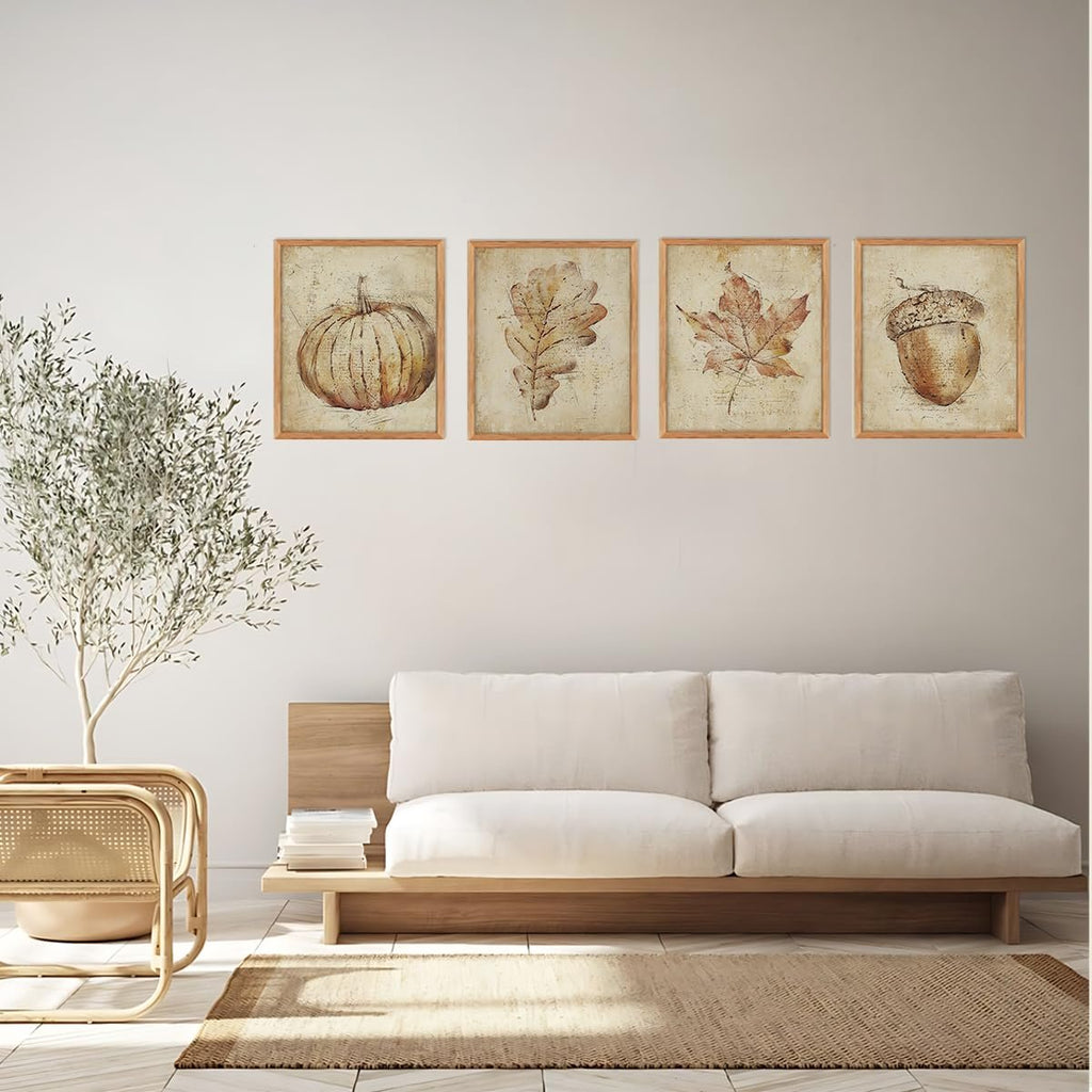 Four unframed vintage fall wall art prints depicting a pumpkin, oak leaf, maple leaf, and acorn, displayed on a wall above a sofa.