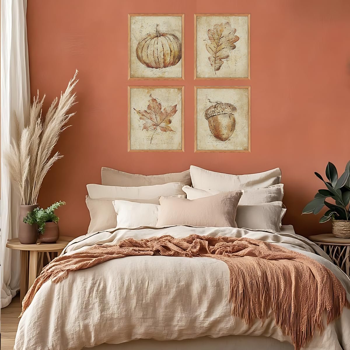 Four framed vintage fall wall art prints featuring a pumpkin, oak leaf, maple leaf, and acorn above a bed.
