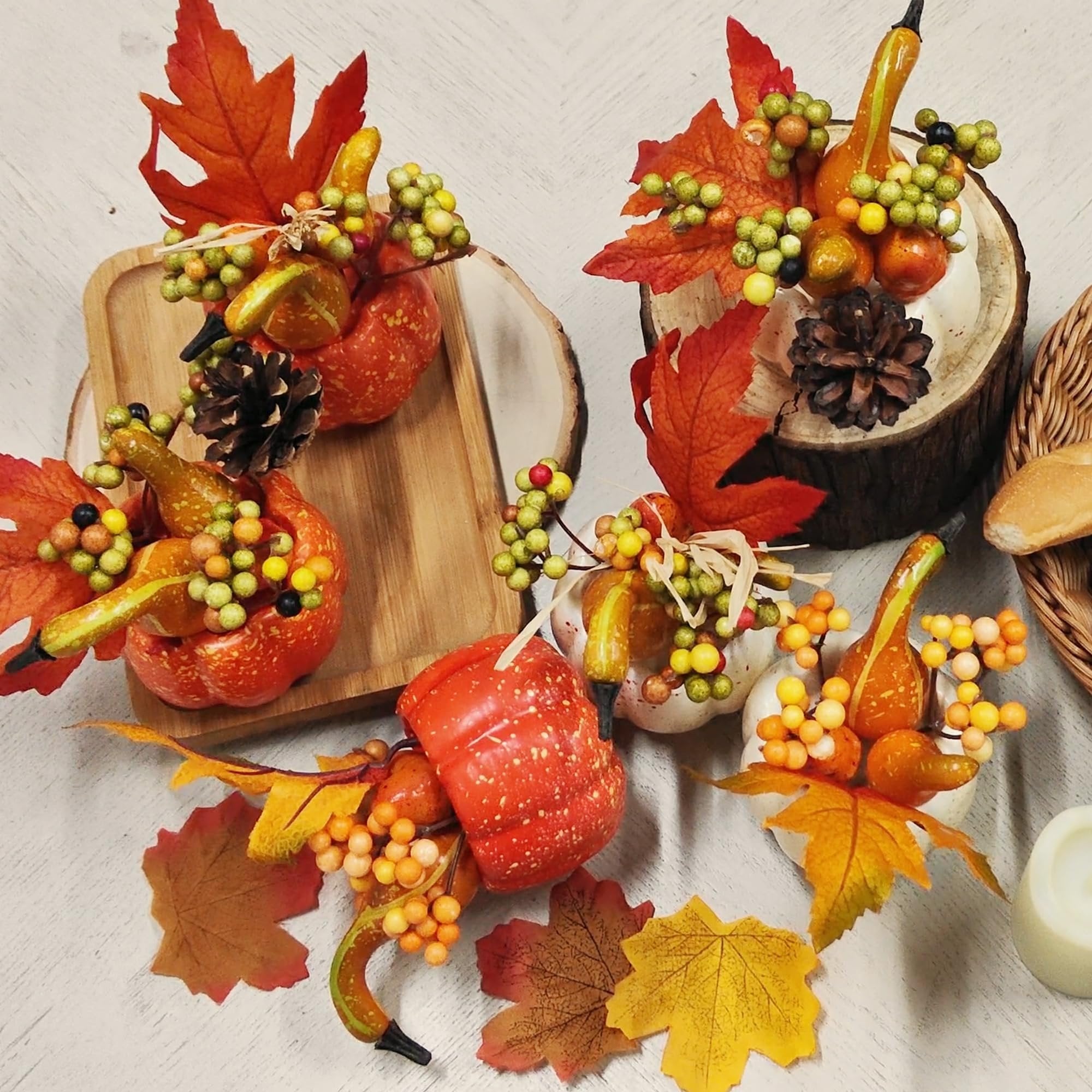Autumnal table centerpieces with pumpkins, gourds, berries, pine cones, and fall leaves.