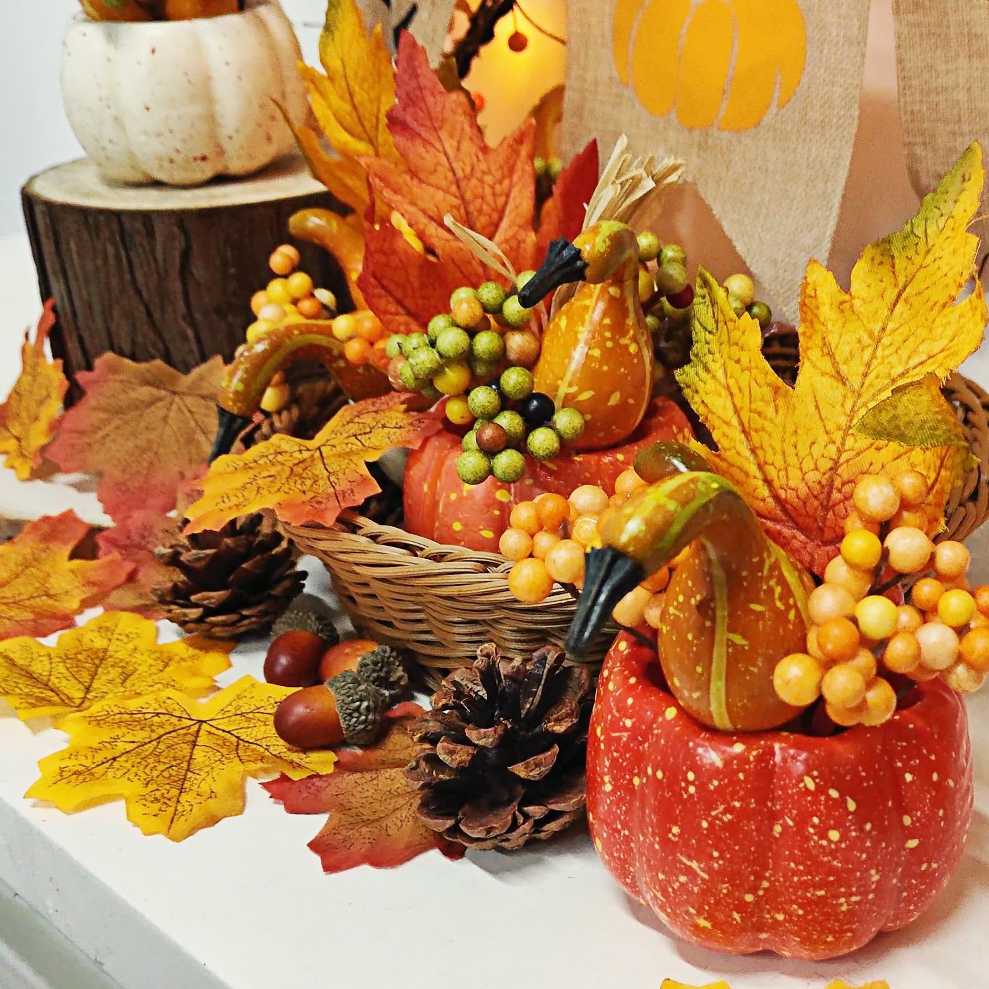 Fall centerpiece with artificial pumpkins, berries, pine cones, acorns, and autumn leaves arranged in a basket and pumpkin holder.