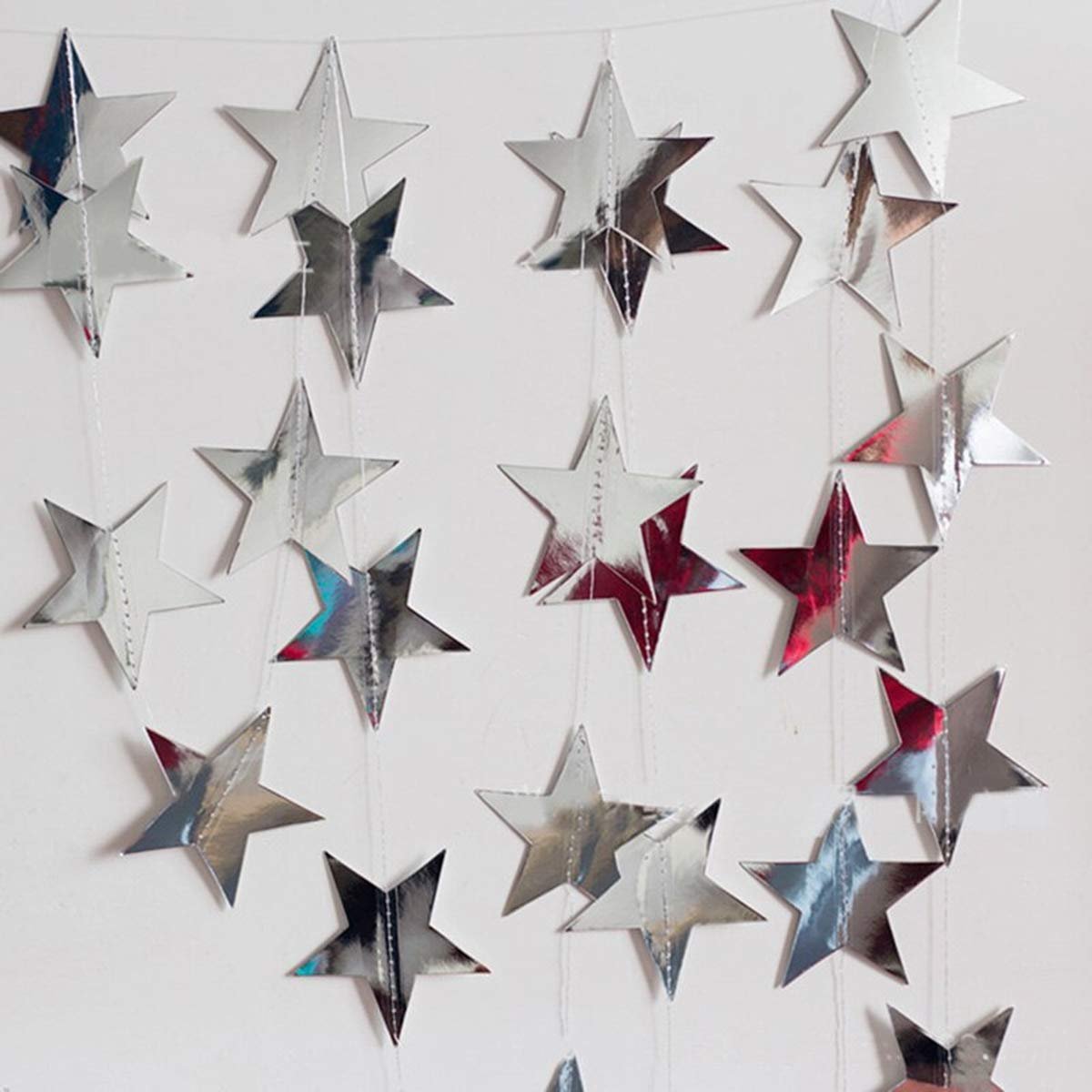 Silver glitter star paper garland decorations hanging against a white background.