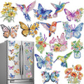 Diamond painting refrigerator magnets in various shapes including butterflies, hummingbirds, flowers, and floral arrangements, displayed on a stainless steel refrigerator.