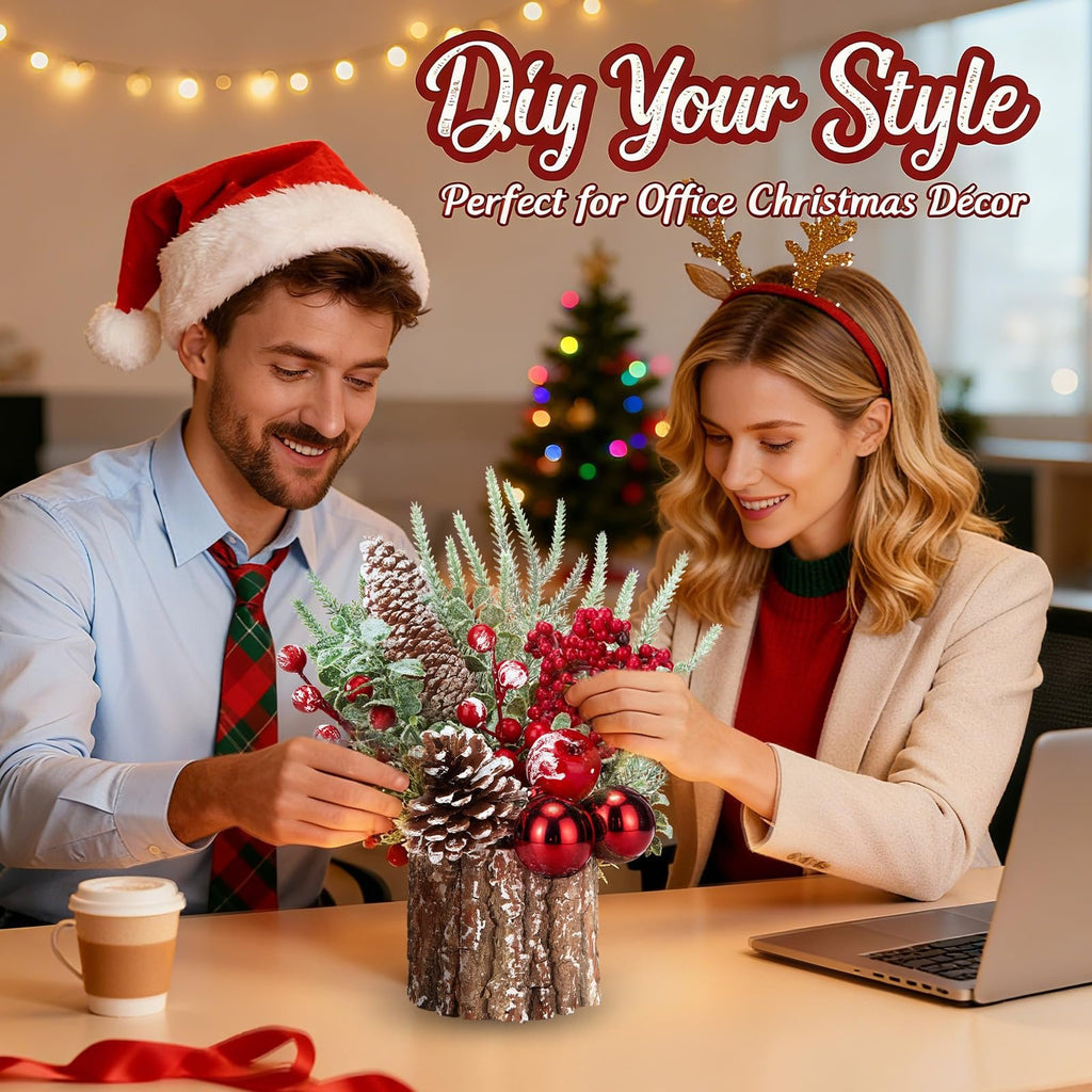 Couple decorating a tabletop Christmas tree with pinecones and red ornaments in an office setting