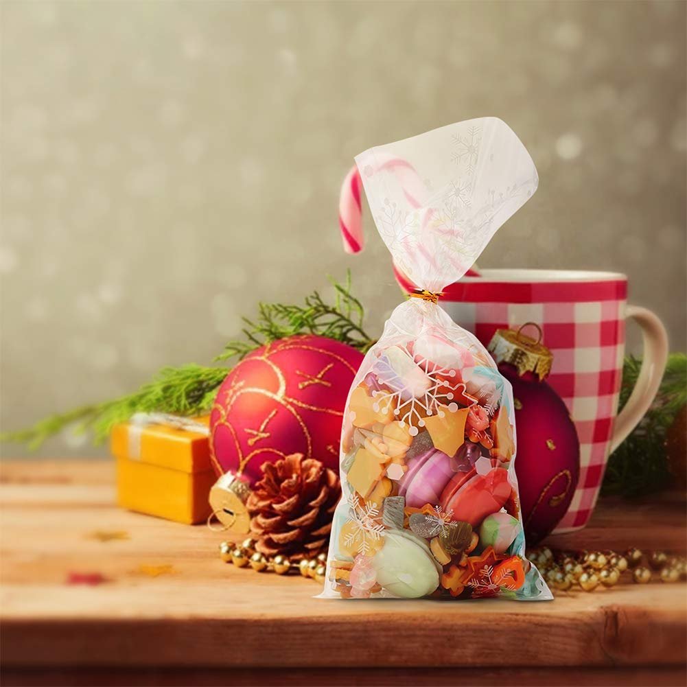 Snowflake cellophane treat bag filled with candy, next to Christmas ornaments and a mug.