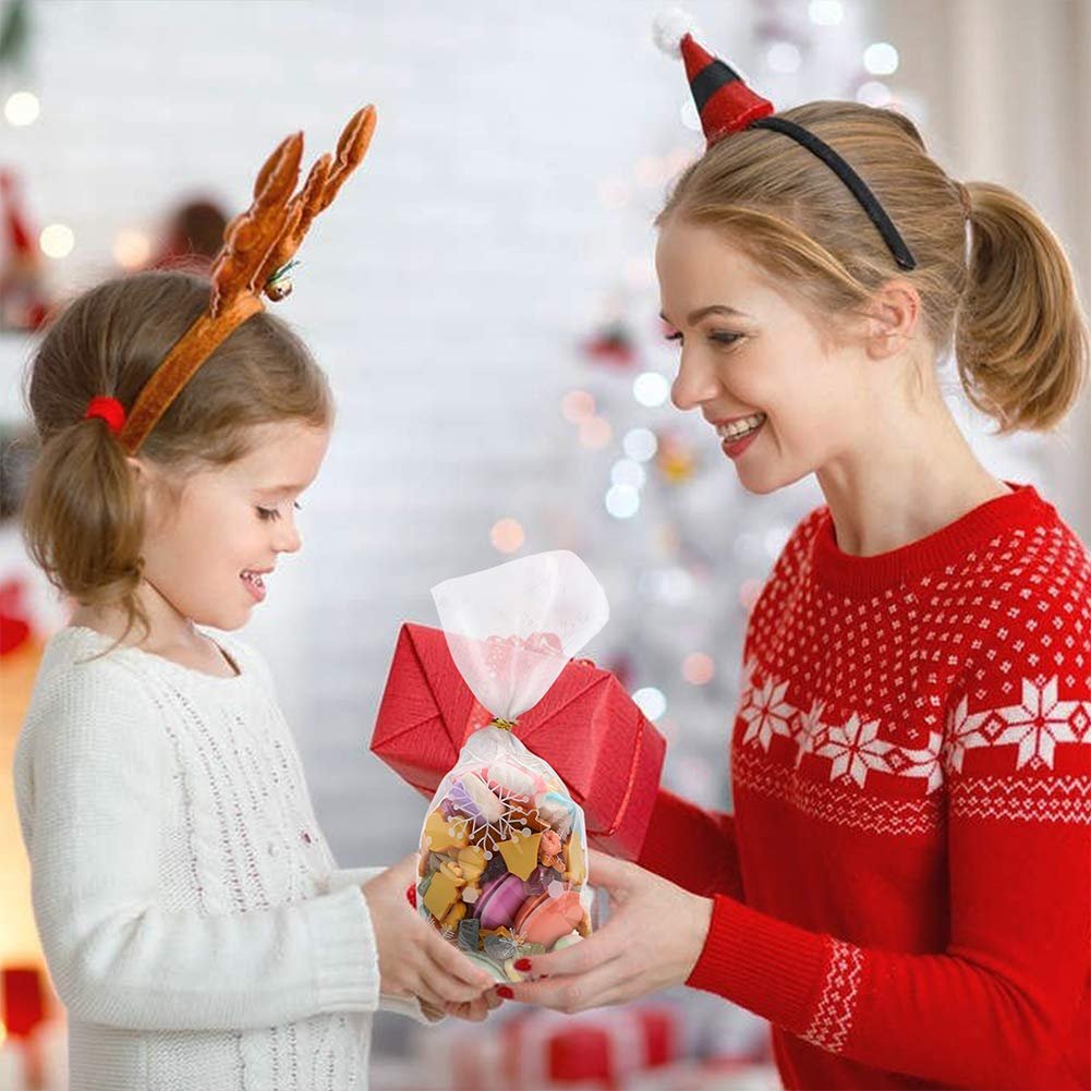 Woman giving a bag of holiday treats to a child, both wearing festive attire.