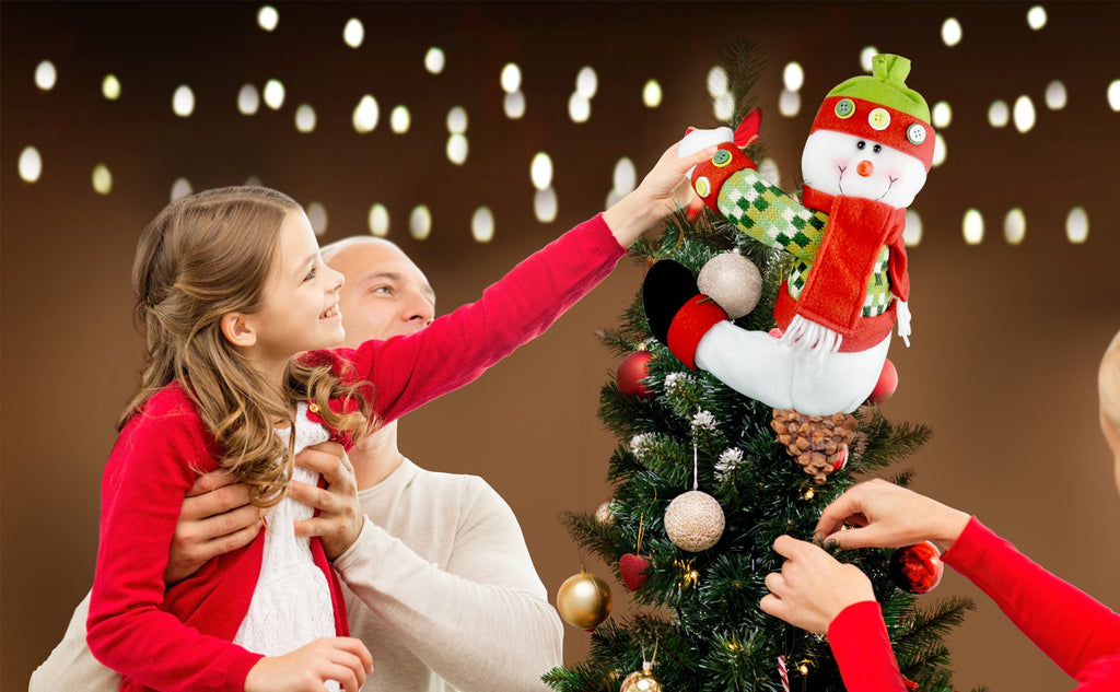 Family decorating a Christmas tree with a plush snowman topper