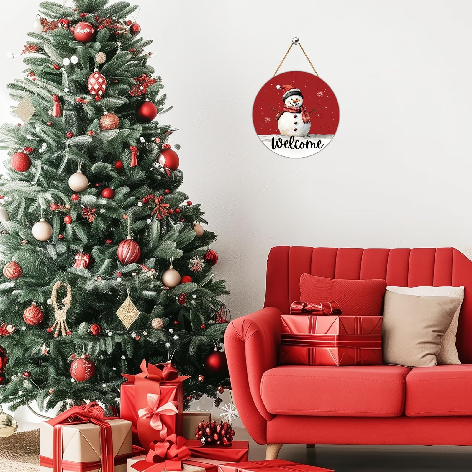 Round wooden snowman welcome door hanger with red background, displayed next to a Christmas tree and red sofa.